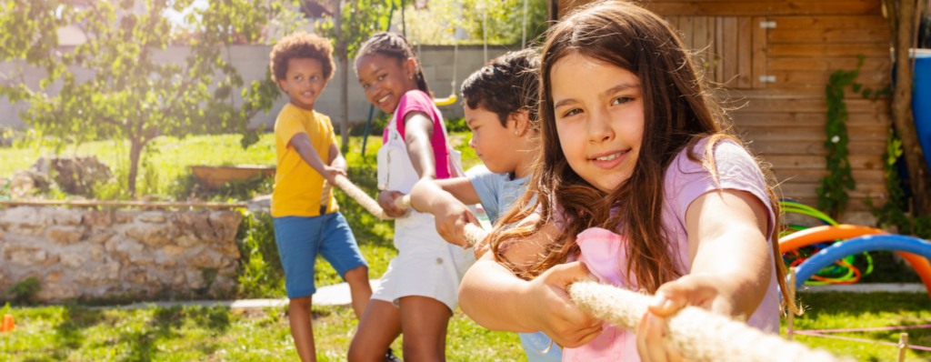 Children playing tug of war at a summer camp, illustrating TEFL summer camp jobs and teaching English through fun outdoor activities