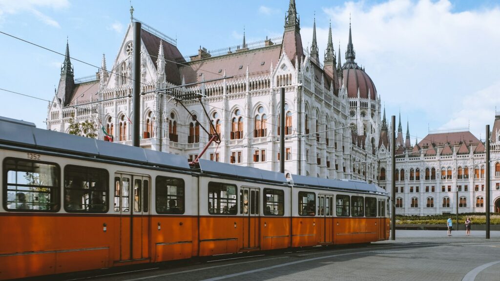 Vintage yellow tram passing grand buildings near the Hungarian Parliament in central Budapest