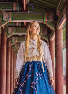 TEFL Courses Online, Solo traveller wearing traditional Korean hanbok at a palace in South Korea, demonstrating safe solo teaching abroad with cultural experiences.