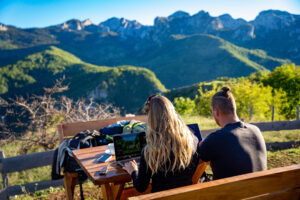 Digital nomad china, Travel influencers on laptops in a mountain setting planning TEFL content and remote work