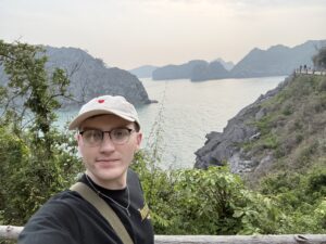 Teaching English in Vietnam, Solo TEFL teacher taking a selfie on a coastal hike, overlooking islands and calm water while teaching English abroad in Vietnam.