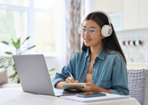 Online teacher planning classes on a tablet and taking notes while studying for a TEFL course