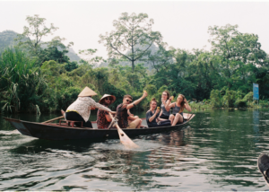 Group of TEFL teachers abroad on a small boat tour through lush green river scenery during a weekend travel experience