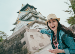 Excited traveller exploring a Japanese castle, showing the lifestyle that comes with teaching English in Japan without experience