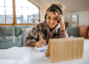 Online TEFL student wearing headphones and studying on a laptop from home