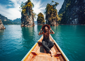 TEFL abroad bucket list adventure – young woman on a wooden boat exploring a tropical lake surrounded by limestone cliffs