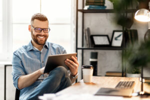 Young man using a tablet at his desk researching how to teach English abroad without a degree