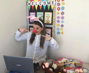 Online TEFL teacher wearing fun bunny ears teaching young learners in a colourful virtual classroom