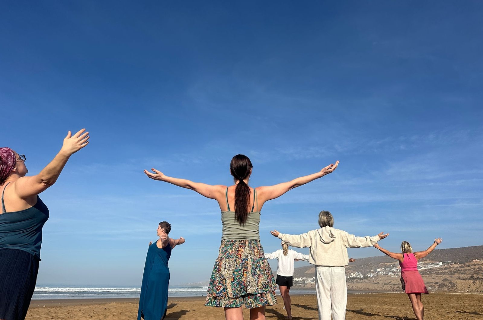 Group of TEFL teachers practising Qigong on the beach during a Moonrise wellbeing session